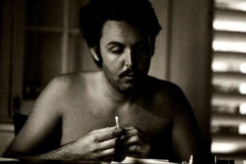 Paul McCarney without a shirt rolling a doobie